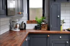 a graphite grey kitchen with a dark stained butcher block countertop that enriches the look of the space