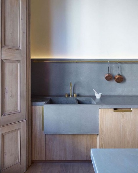 a minimalist kitchen with light colored wooden cabinets is made bolder with concrete touches