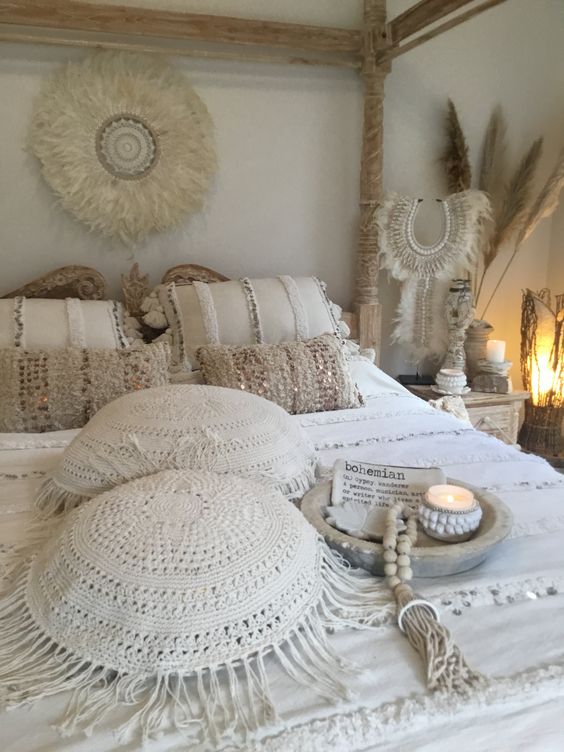 a neutral Moroccan bedroom with Moroccan pillows and a fringe blanket, pampas grass, feather and bead decor