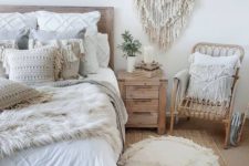 a neutral boho room with layered tassel and frigne pillows, a large fringe pillow, a macrame hanging and rattan furniture