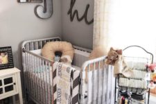 a vintage farmhouse nursery with a white crib, a metal shelf, a pretty gallery wall and textiles to cozy it up
