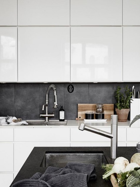 a white contemporary kitchen with a concrete tile backsplash and a matching tabletop of black concrete