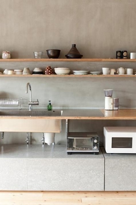 an airy modern kitchen with plywood shelves and a countertop and a concrete backsplash