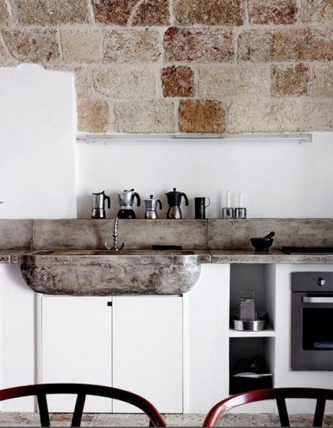 masonry and a concrete backsplash and countertops echo and make the all-white space softer and cozier