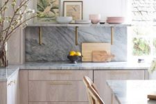 02 a chic contemporary kitchen with neutral cabinets, a grey kitchen backsplash and countertops and touches of gold for more chic