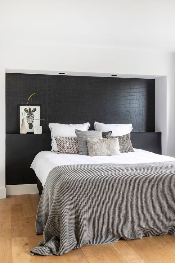 a Nordic bedroom with a black statement wall that imitates reptile skin and is a unique and dramatic accent