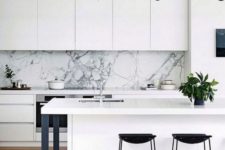 10 a minimalist monochromatic kitchen with sleek white cabinets, black stools and lamps and a gorgeous white marble backsplash