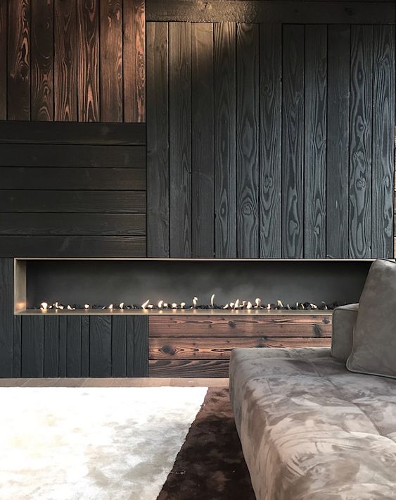 an accent wall clad with black wood in a catchy pattern and with a built-in fireplace is a bold statement for the whole space
