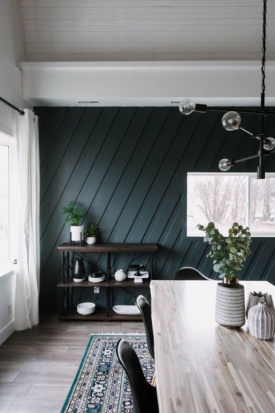 a modern farmhouse living room with a black paneled accent wall that adds drama, chic and eye catchiness to the space