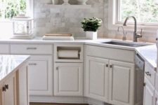 26 a white farmhouse kitchen with a marble tile backsplash, a white countertop and neutral fixtures for a cohesive feel