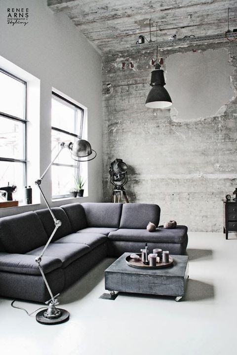 a Nordic meets industrial living room with a shabby wooden wall, a concrete table, metal lamps and some greenery in pots