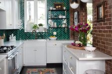 a U-shaped white kitchen with a bold emerald herringbone tile backsplash and cool pendant lamps