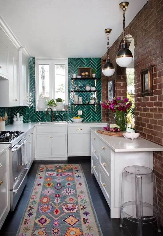 A U shaped white kitchen with a bold emerald herringbone tile backsplash and cool pendant lamps