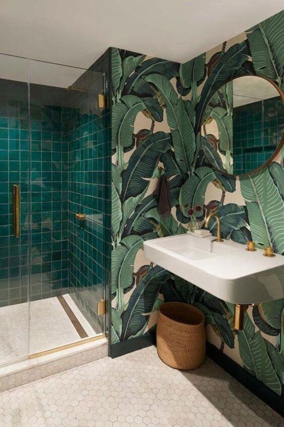 a beautiful bathroom with tropical print wallpaper, emerald square tiles in the shower, hex tiles, a wall-mounted sink and a mirror