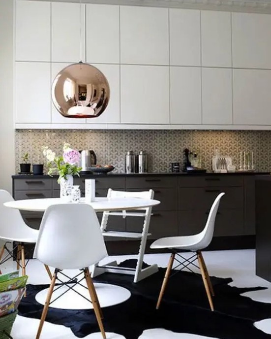A black and white mid century modern kitchen with a white dining set, a mosaic tile backsplash and a large copper lamp