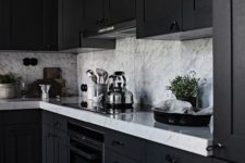 a black framhouse kitchen with white marble countertops and a backsplash is a chic and stylish idea