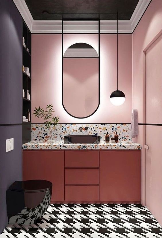 a bold bathroom with pink walls, a coral vanity, a terrazzo countertop and bold graphic tiles on the floor