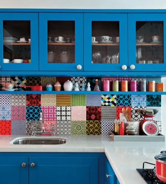 a bold blue kitchen with a super colorful mismatching tile backsplash and colorful accessories to support the colors of the backsplash