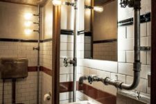 a bold industrial powder room with various tiles, exposed piping, metal fixtures and stands plus bulbs