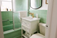 a bright and fun bathroom clad with light green tiles, with a green tub, white appliances and a white vanity