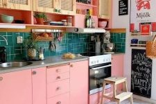 a bright maximalist kitchen with rattan and pink cabinets, a green tile backsplash, a bright printed rug and colorful art
