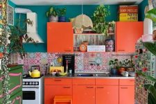 a bright orange kitchen with colorful mismatching tiles, blue walls, a green sideboard, potted plants and a colorful rug