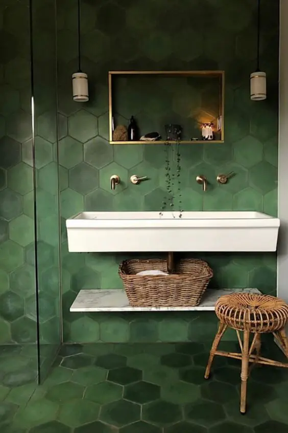 a catchy green bathroom with hex tiles, a wlal mounted sink, a shelf, a wooden stool and a shelf instead of a mirror