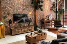 a catchy industrial living room with brick walls, a leather sofa and chair, pallet and crate furniture and cool pendant lamps