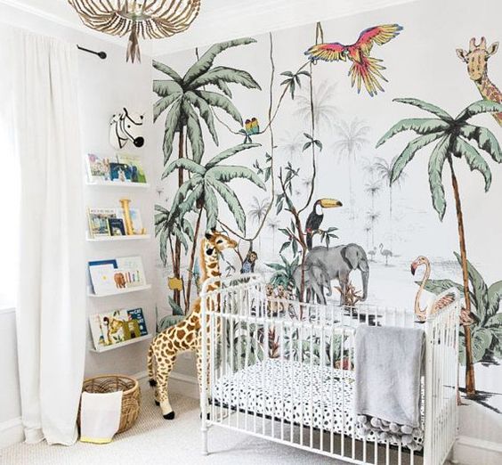 a cheerful jungle nursery with a fun printed statement wall, some shelves, cute toys and a bead chandelier