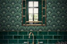 a chic art deco bathroom in green shades, done with tiles and wallpaper, with gold and brass touches looks awesome
