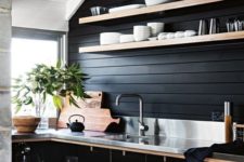a chic black farmhouse kitchen with wooden planks, sleek black plywood cabinets and a metal countertop plus a burlap lamp