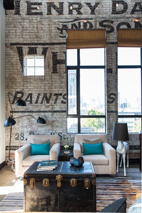 a chic industrial living room with white brick walls with stencils, a vintage chest, comfy furniture and metal lamps