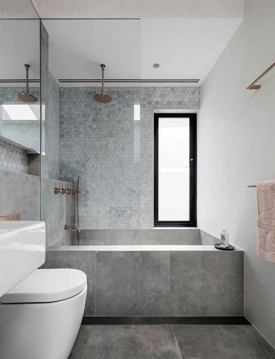 a chic minimalist grey bathroom with marble hex tiles, large scale grey ones and copper fixtures for a warmer touch
