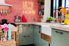 a colorful modern kitchen with mint cabinets, a pink tile backsplash with neon and whte countertops