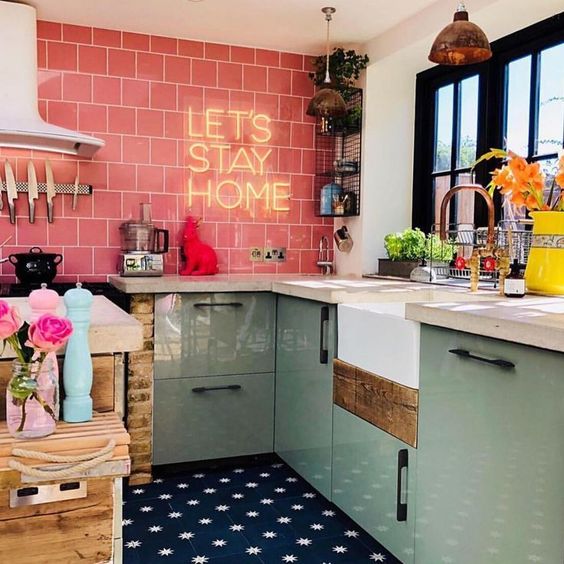 a colorful modern kitchen with mint cabinets, a pink tile backsplash with neon and whte countertops
