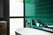 a contemporary bathroom done with a statement wall of emerald tiles and calm grey tiles on the rest of the surfaces
