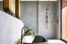 a contemporary bathroom with concrete walls and a floor, a black bathtub, copper fixtures and a glazed wall for more natural light