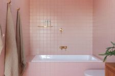 a cool contemporary pink bathroom with white appliancs and gold and copper fixtures plus potted greenery