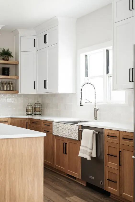 a cool farmhouse kitchen with white and stained cabinets, white countertops, glazed white tiles and black handles