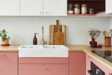 a cool two-tone kitchen with pink and white sleek cabinets, a white skinny tile backsplash and butcherblock countertops