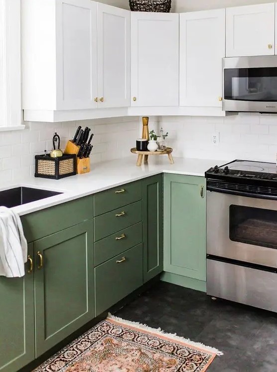 A cool two tone kitchen with white and olive green shaker cabinets, white stone countertops and a white subway tile backsplash and gold knobs