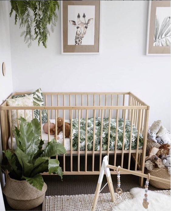 a cute tropical nursery with potted greenery, wooden furniture, a jute rug, baskets with toys and pretty artworks