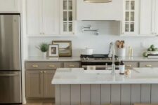 a farmhouse kitchen with two-tone cabinets, a large hood, a large shiplap kitchen island, a brass pendant lamp and wooden stools