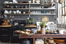 a farmhouse meets industrial kitchen with grey walls, black metal cabinets, a shabby wooden kitchen island and exposed pipes
