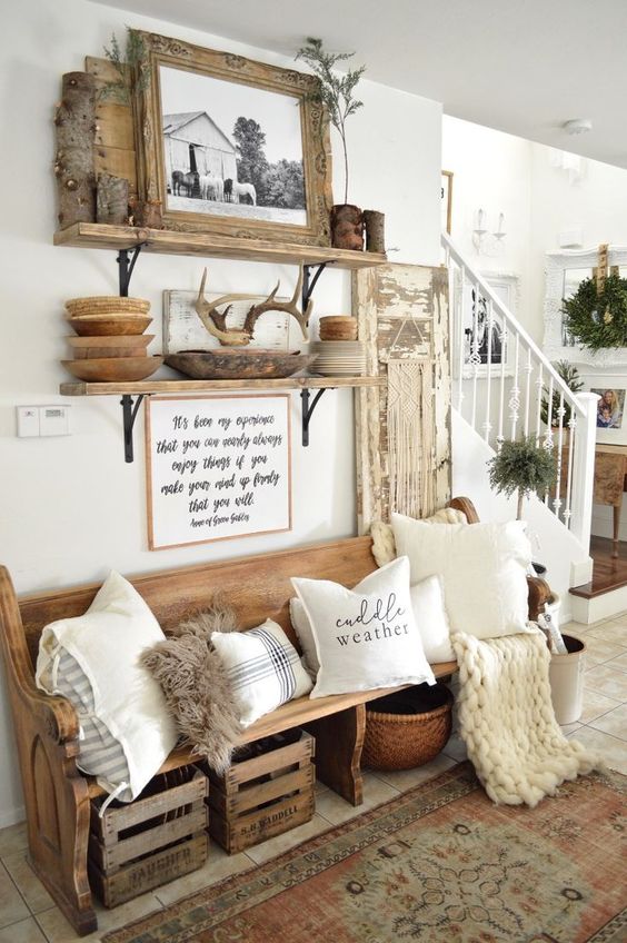 a farmhouse meets woodland entryway with a wooden bench, some crates and baskets, open shelving, antlers and branches