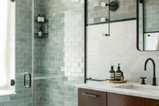 a farmhouse sage green bathroom clad with subway tiles, a dark-stained floating vanity and black fixtures