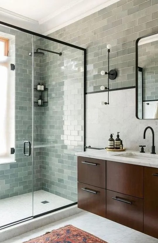 a farmhouse sage green bathroom clad with subway tiles, a dark stained floating vanity and black fixtures