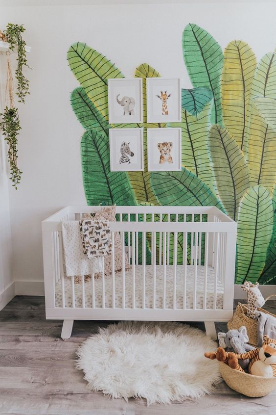 a fun tropical nursery with a painted leaf wall, pretty artworks, toys in baskets and a faux fur rug