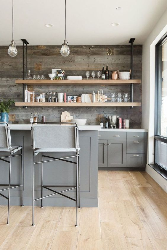 a gorgeous farmhouse kitchen with grey cabinets, open industrial shelving and a reclaimed wooden backsplash looks chic