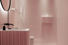 a gorgeous pink bathroom all clad with tiles, with floating elements and black touches for drama